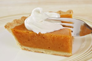 Slice of freshly baked pumpkin pie with whipped cream and fork.
